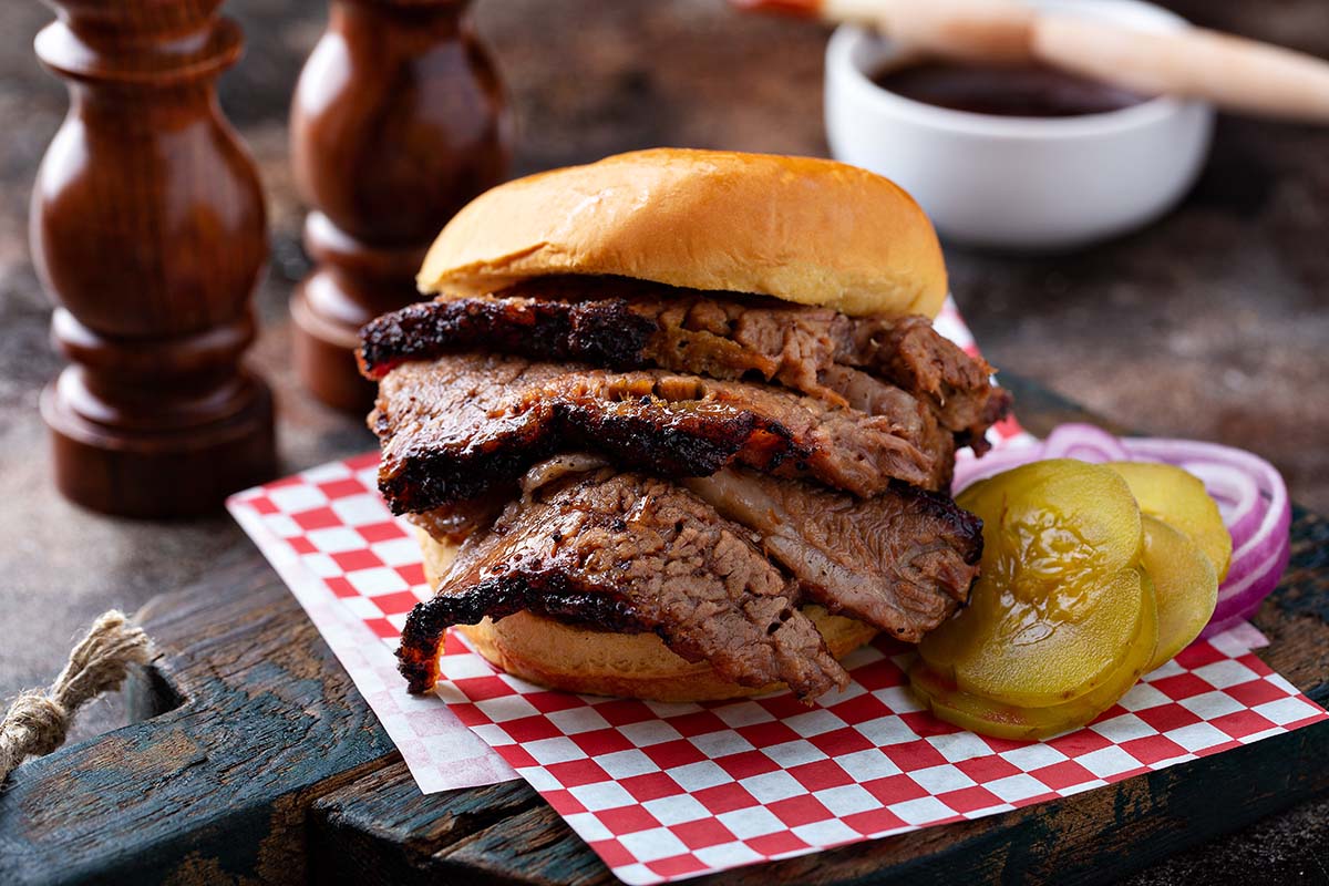 Traeger brisket sandwich with pickles and onions on the side. 