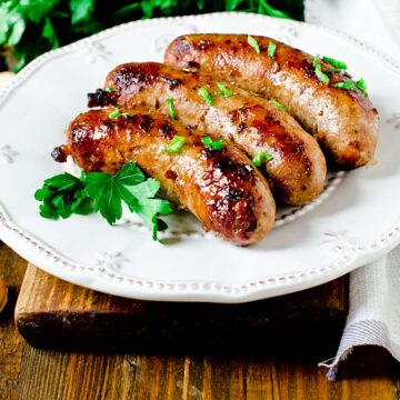 Three Italian sausages on a white plate.