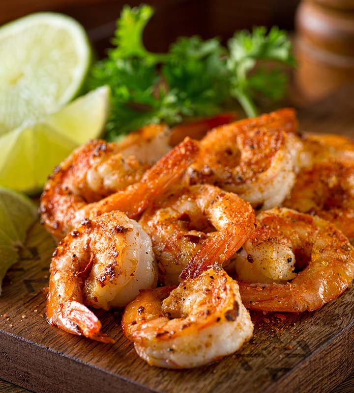 old bay shrimp with lime wedges on a wooden board.