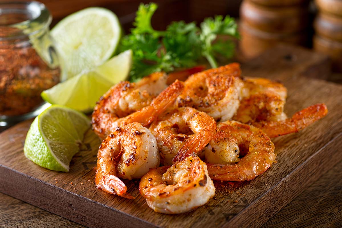 old bay shrimp with lime wedges on a wooden board. 