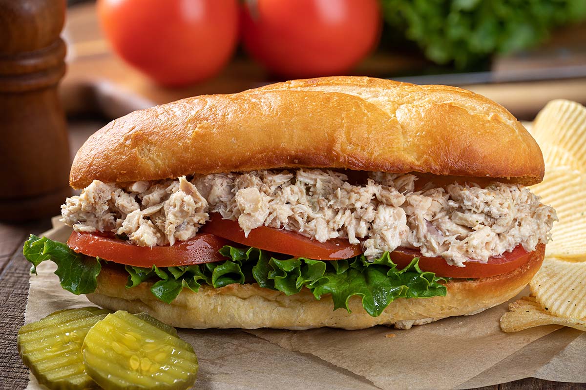 albacore tuna salad sandwich with pickles and chips on the side. 