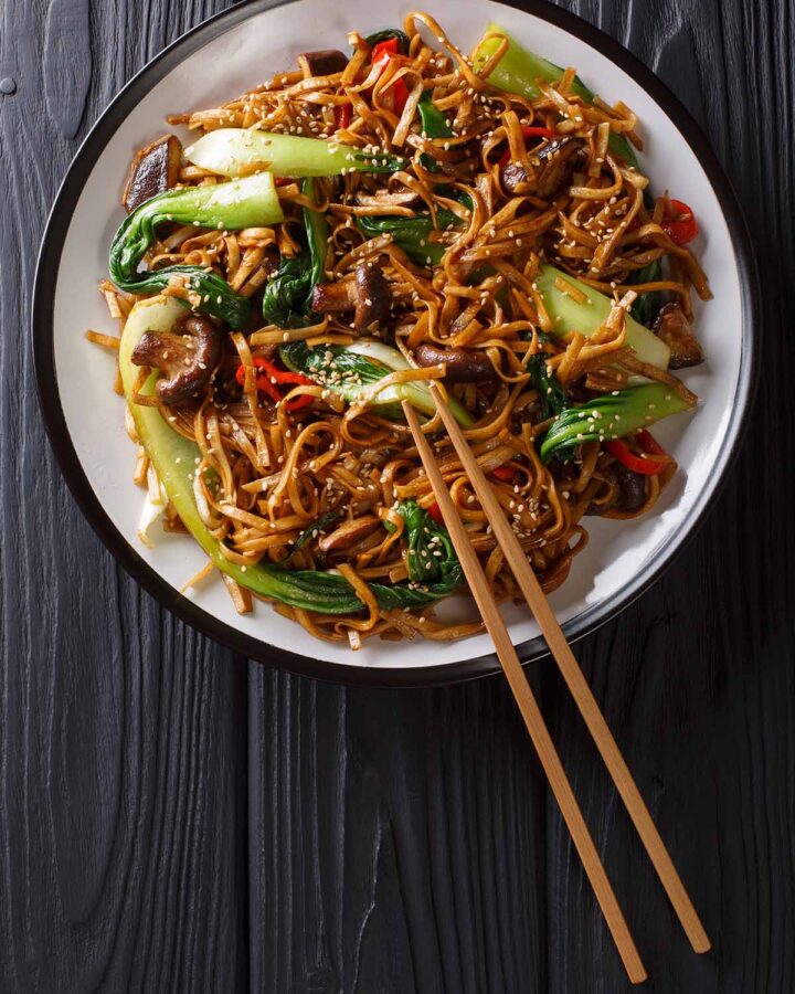 black garlic noodles in a bowl with chopsticks on the side.