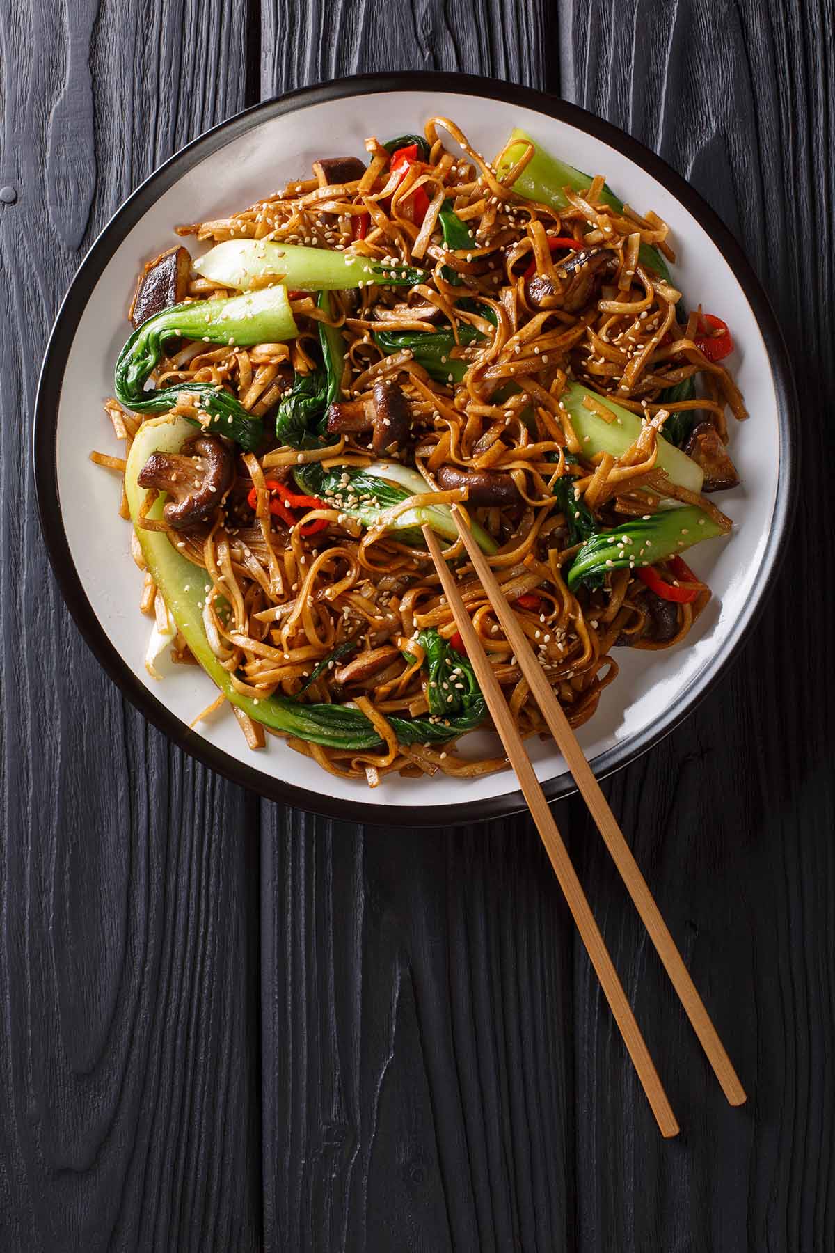 black garlic noodles in a bowl with chopsticks on the side.