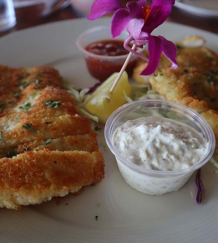 calamari steaks with tartar sauce, cocktail sauce, and a lemon wedge on the side.