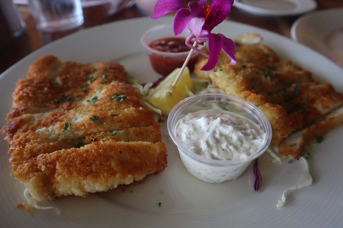 calamari steaks with tartar sauce, cocktail sauce, and a lemon wedge on the side. 