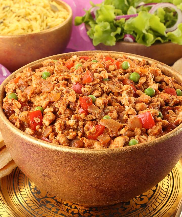 chicken keema in a bowl with rice on the side.