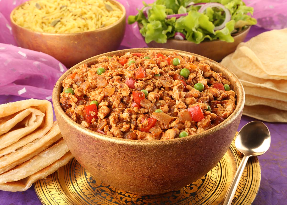 chicken keema in a bowl with rice on the side.