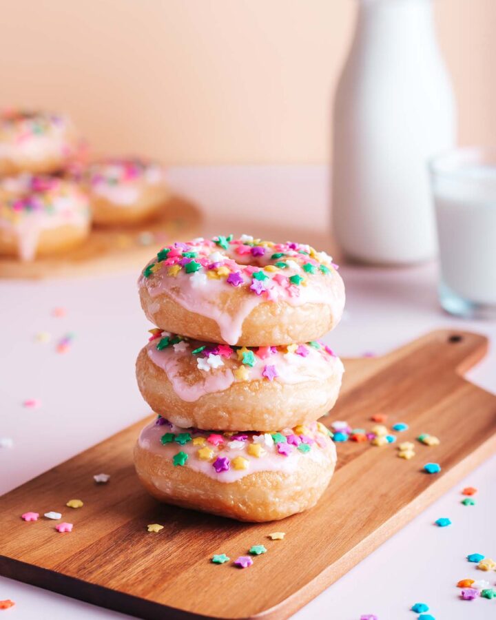 Three stacked mini donuts with milk in the background.