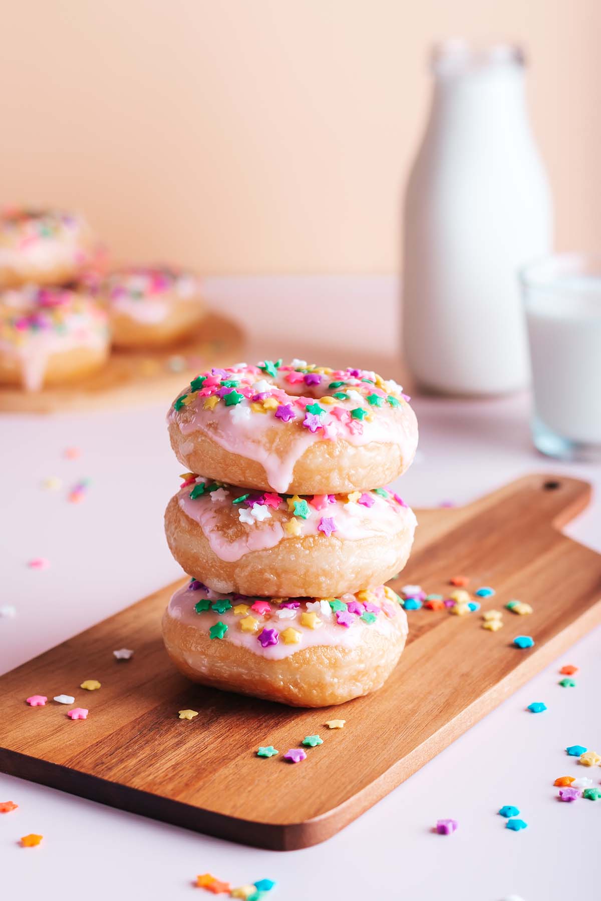 Three stacked mini donuts with milk in the background. 