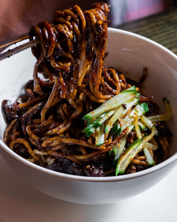 vegan korean noodles in a white bowl with chopsticks.