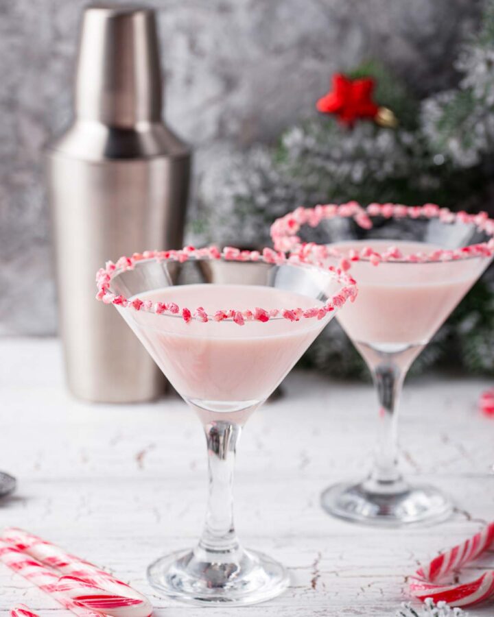 two white chocolate peppermint martinis with a tumbler in the background.