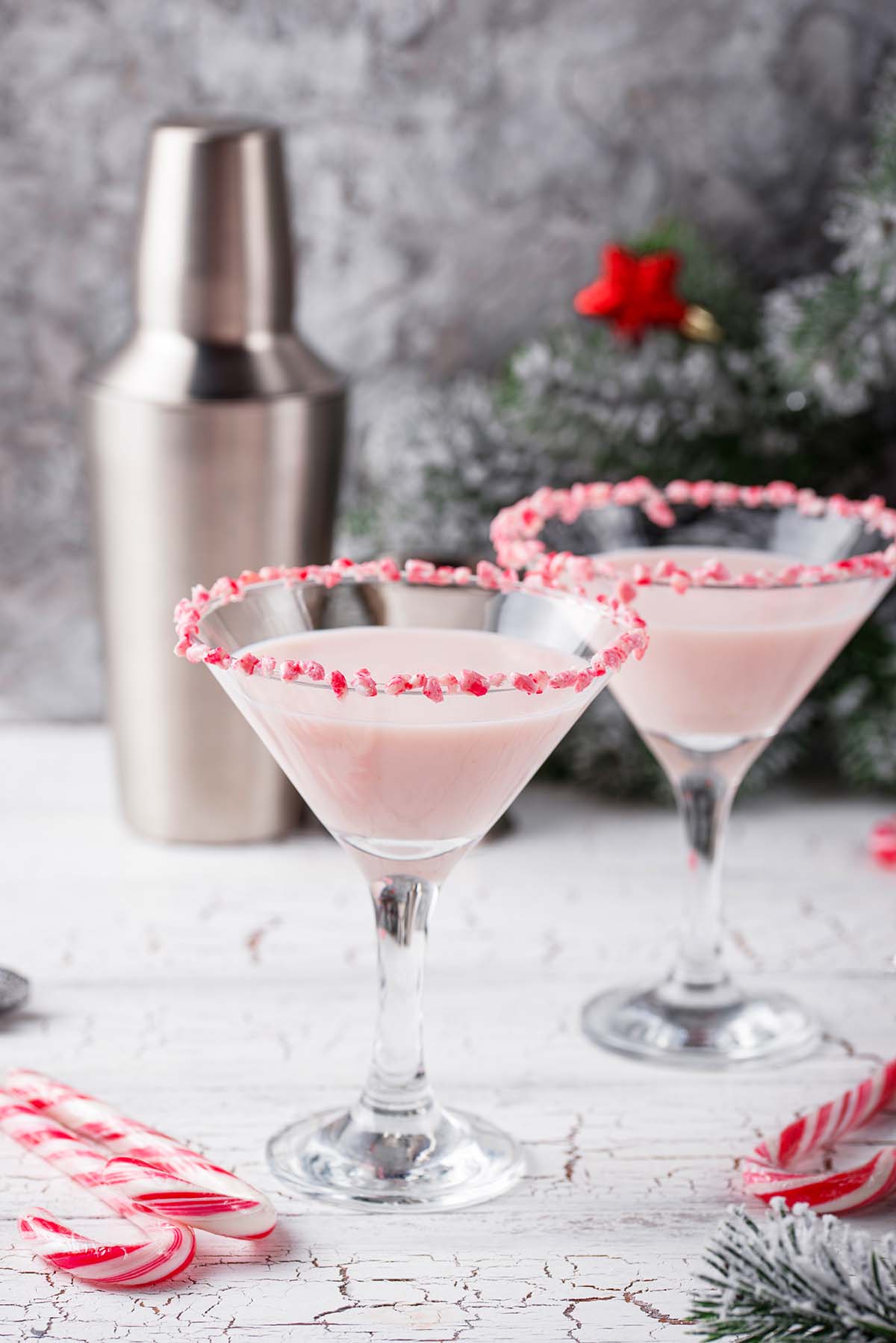 two white chocolate peppermint martinis with a tumbler in the background. 