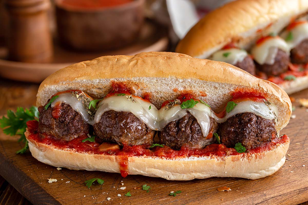ground pork meatball sandwich with cheese and sauce.