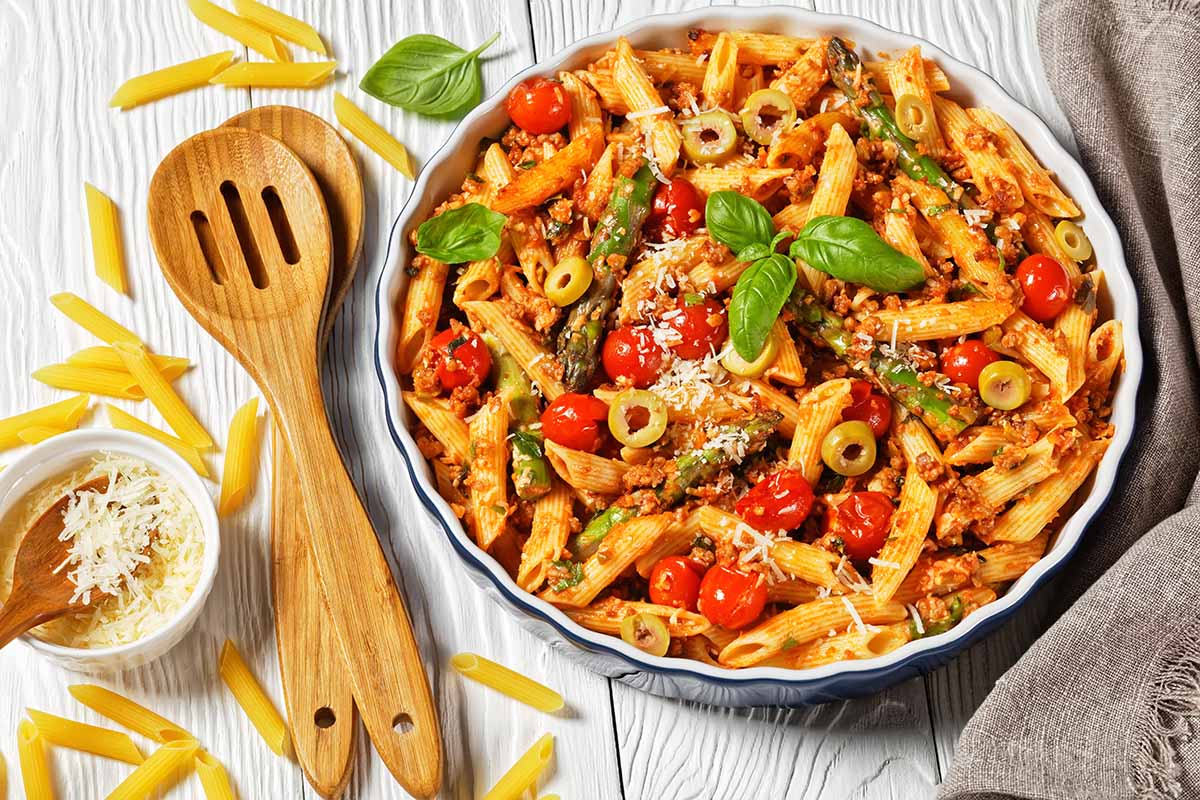 ground turkey pasta in a white bowl with wooden spoons on the side. 