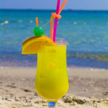 green jungle juice in a glass with straws.