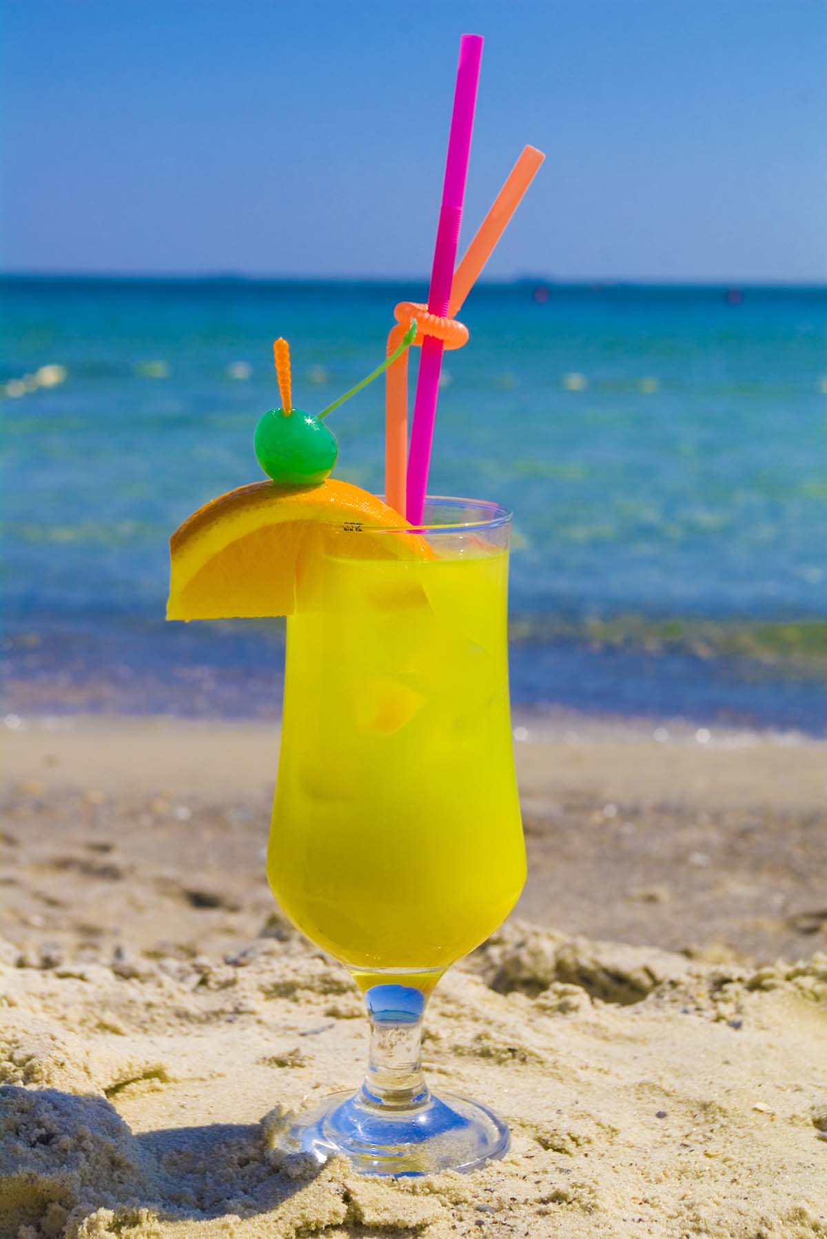 green jungle juice in a glass with straws.