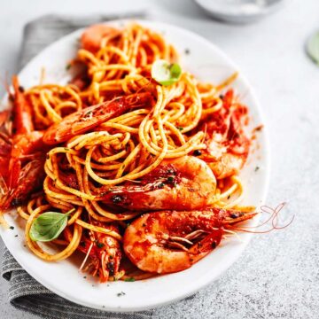 langostino pasta with red sauce in a white bowl.