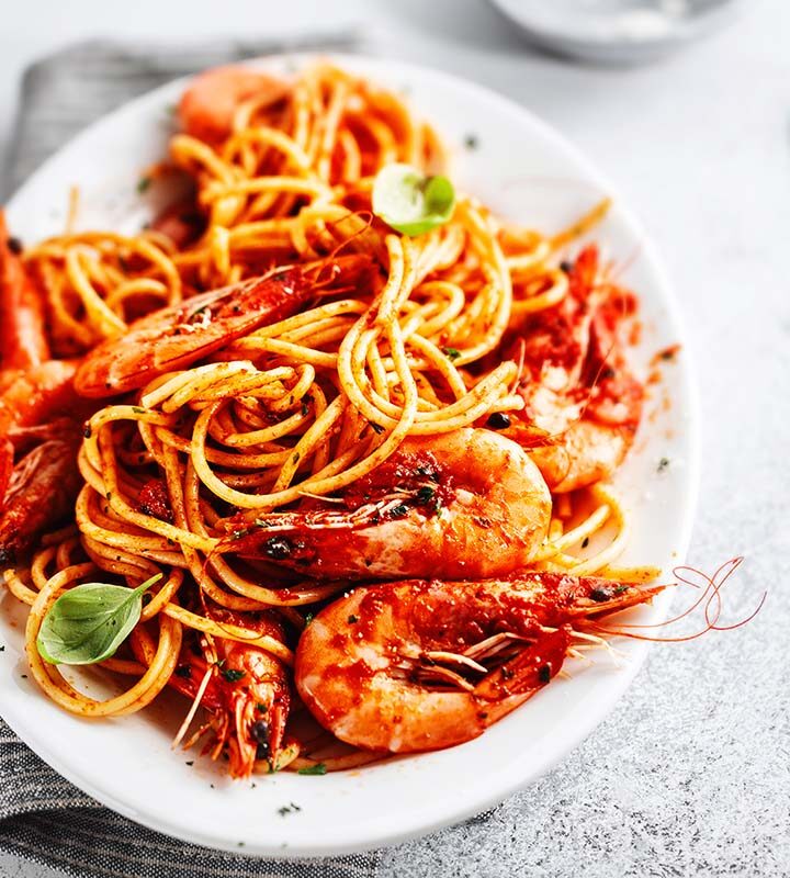 langostino pasta with red sauce in a white bowl.