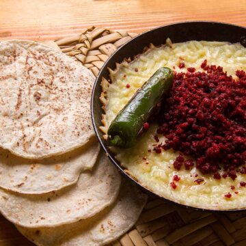 soyrizo queso dip in a skillet with tortillas on the side.