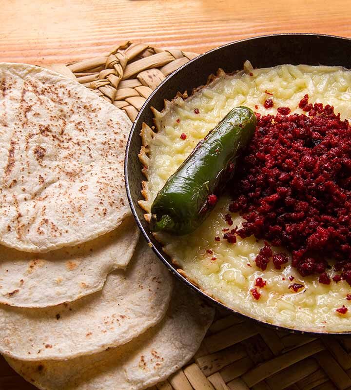 soyrizo queso dip in a skillet with tortillas on the side.