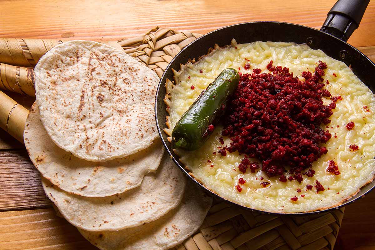 soyrizo queso dip in a skillet with tortillas on the side.