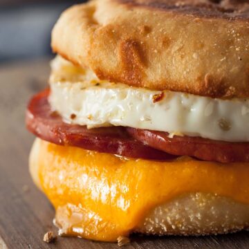 taylor ham, egg, and cheese breakfast sandwich on a wooden board.