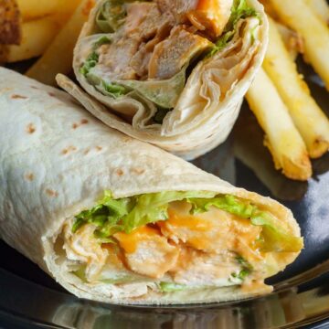chicken wrap on a plate with fries.