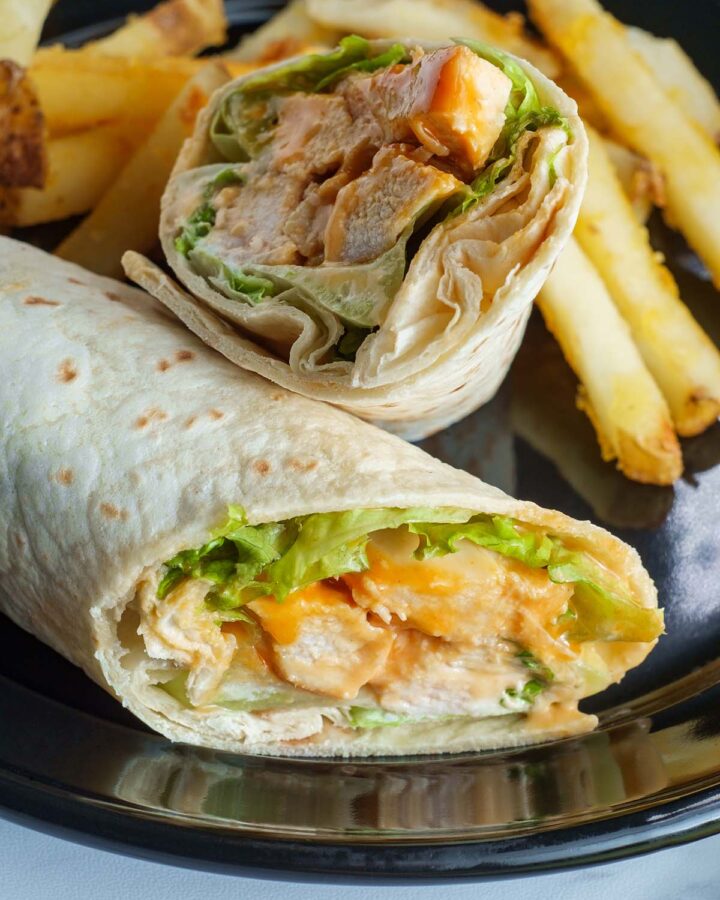 chicken wrap on a plate with fries.