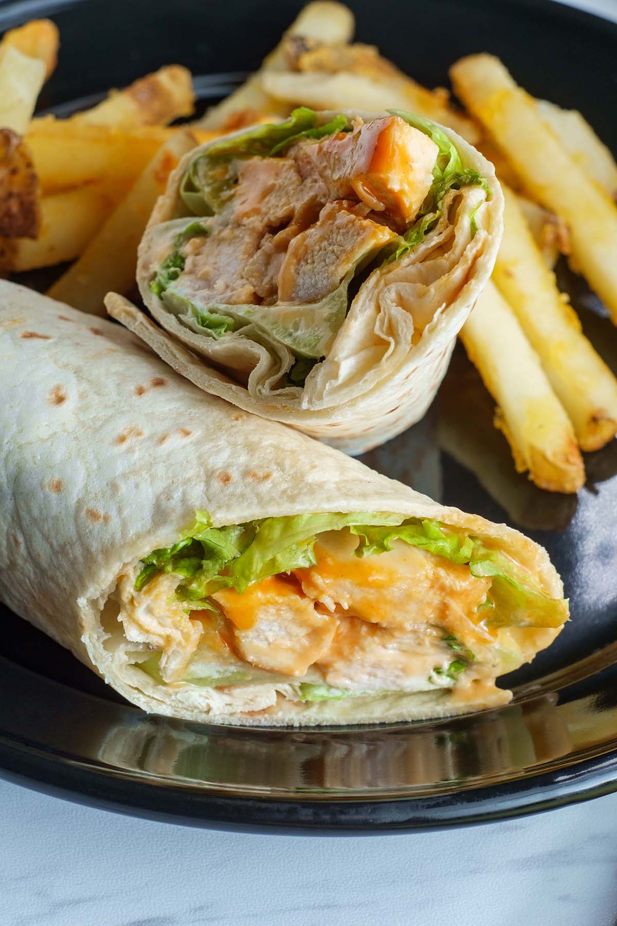 chicken wrap on a plate with fries.