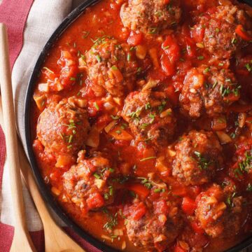cooked meatballs in marinara sauce with wooden spoons on the side.