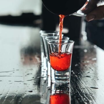 Tumbler pouring a peanut butter and jelly shot into a shot glass.