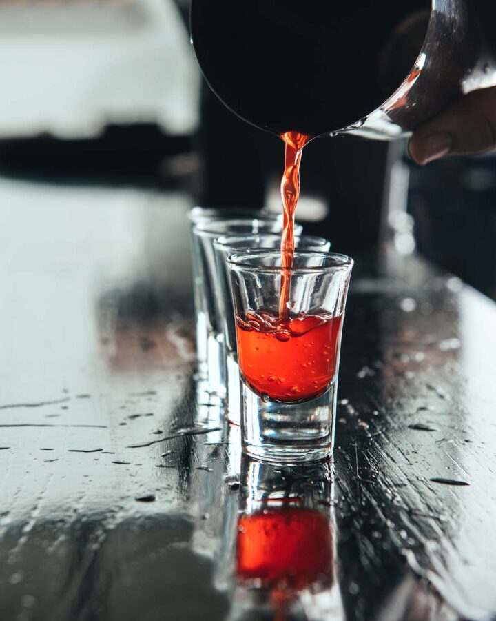 Tumbler pouring a peanut butter and jelly shot into a shot glass.