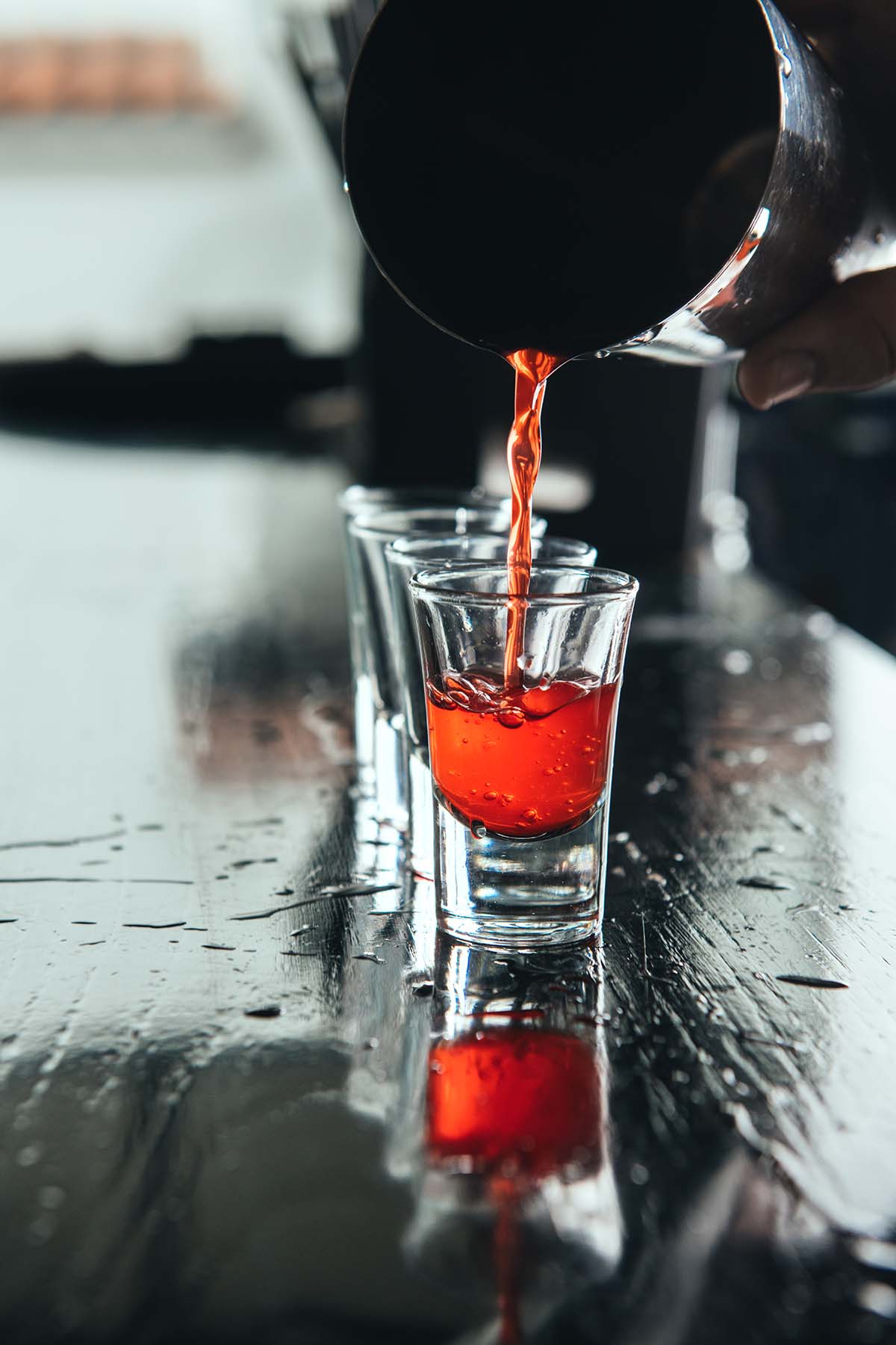 Tumbler pouring a peanut butter and jelly shot into a shot glass. 