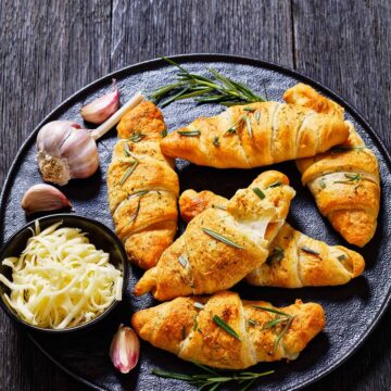 cheese stuffed crescent rolls with rosemary, garlic, and shredded white cheese on the side.