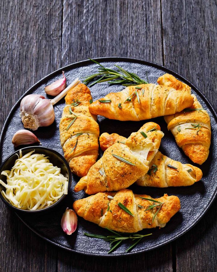cheese stuffed crescent rolls with rosemary, garlic, and shredded white cheese on the side.