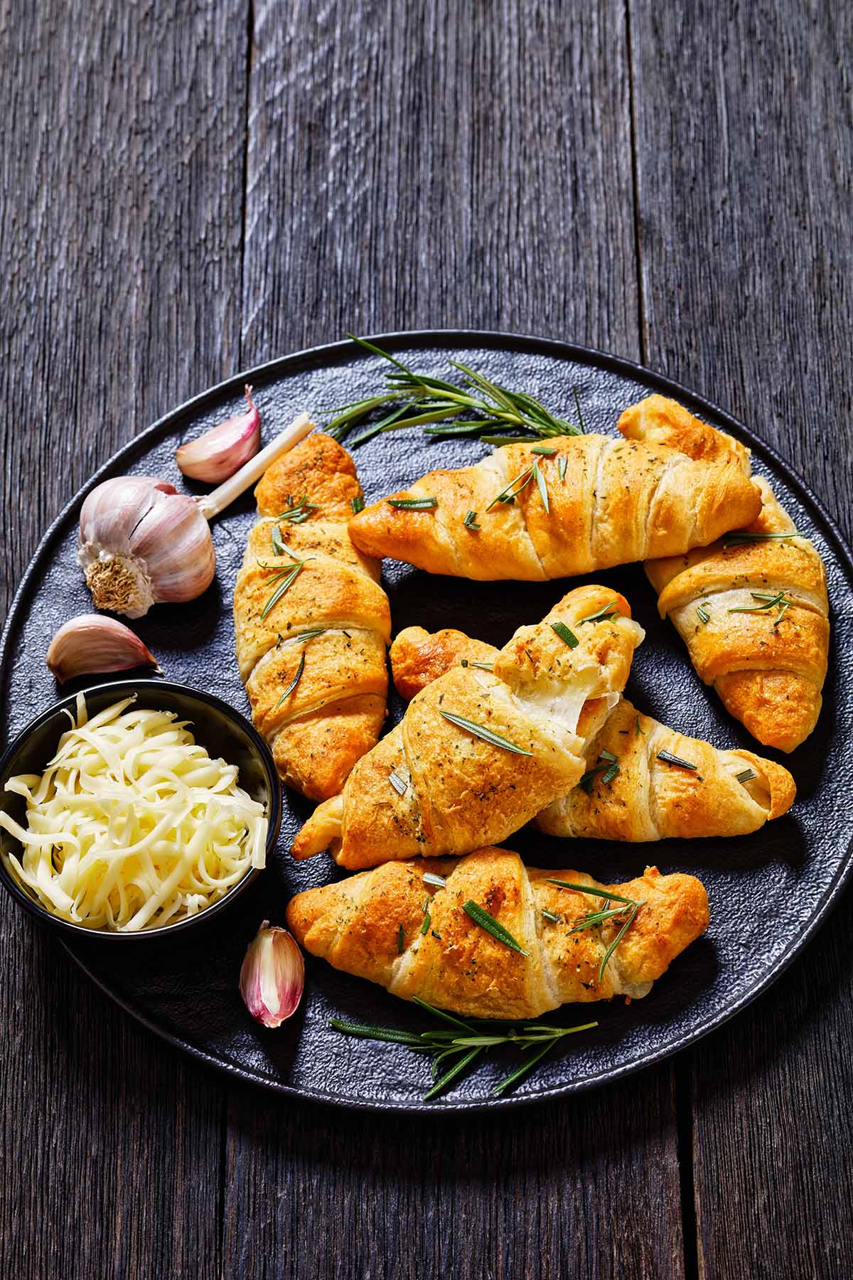 cheese stuffed crescent rolls with rosemary, garlic, and shredded white cheese on the side. 