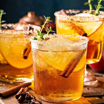 Three crown apple cocktails on a wooden board.