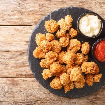 crispy alligator bites on a plate with ketchup on the side.