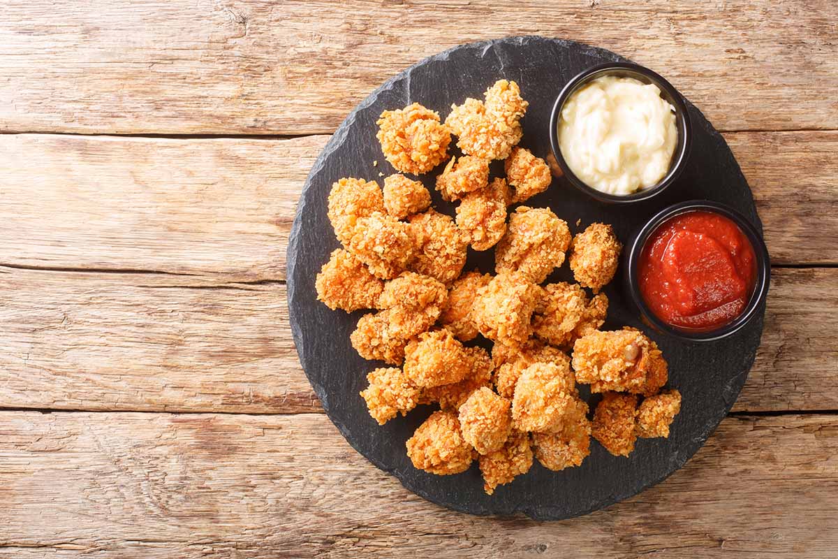 crispy alligator bites on a plate with ketchup on the side.