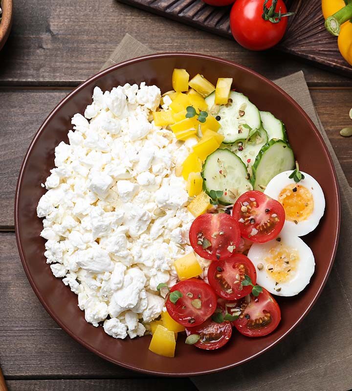 cottage cheese in a bowl with tomatoes, eggs, peppers, and cucumbers.