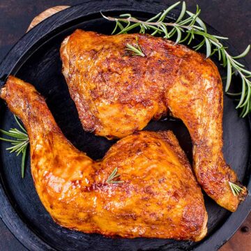 two grilled chicken leg quarters on a plate.