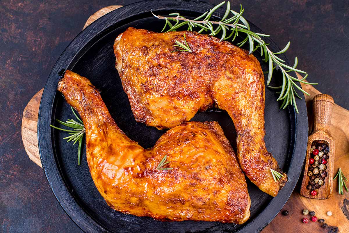 two grilled chicken leg quarters on a plate.