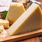 a block of romano cheese on a wooden board.