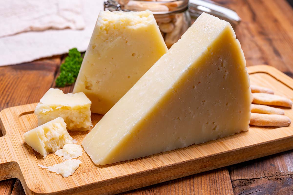 a block of romano cheese on a wooden board.