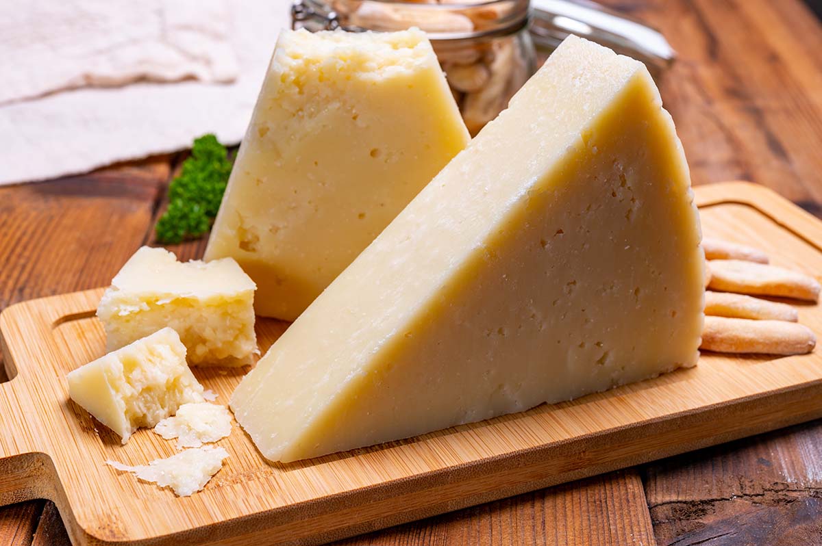 a block of romano cheese on a wooden board. 