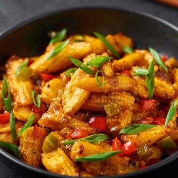 baby corn in a bowl with scallions and peppers.