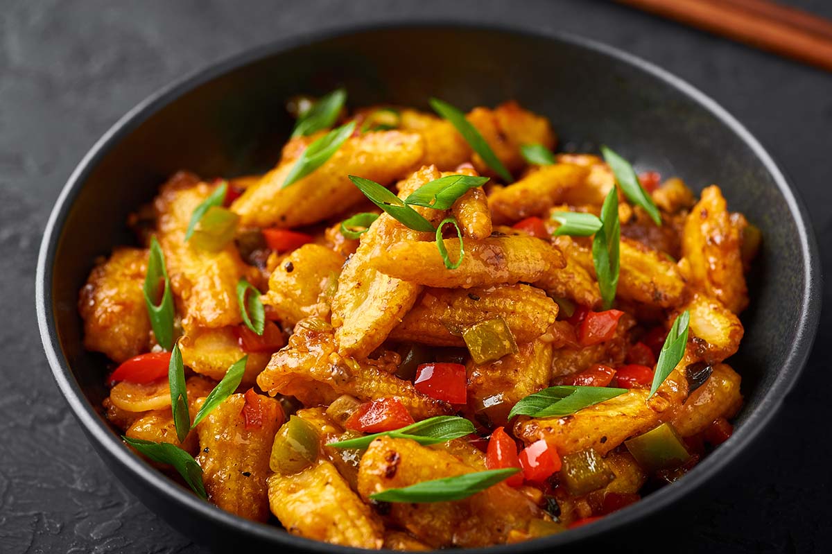 baby corn in a bowl with scallions and peppers. 