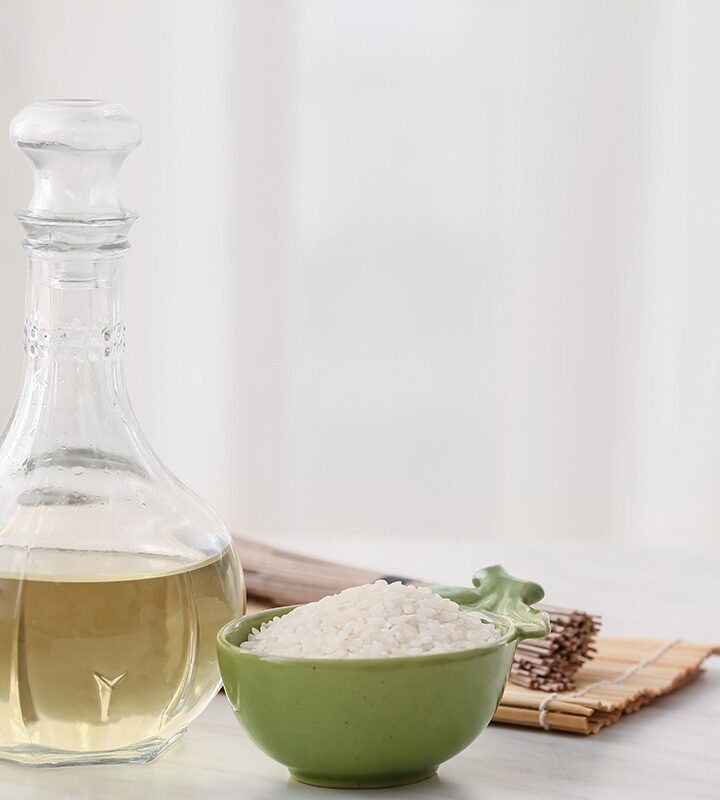 Rice vinegar in a glass bottle with a bowl of white rice on the side.