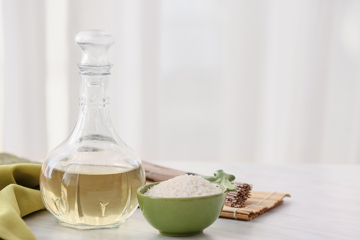 Rice vinegar in a glass bottle with a bowl of white rice on the side. 